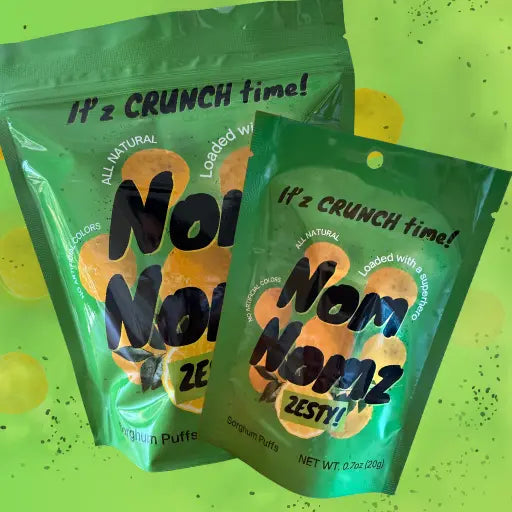 Two green packages of Nom Nomz Zesty! snack puffs on a bright green background.